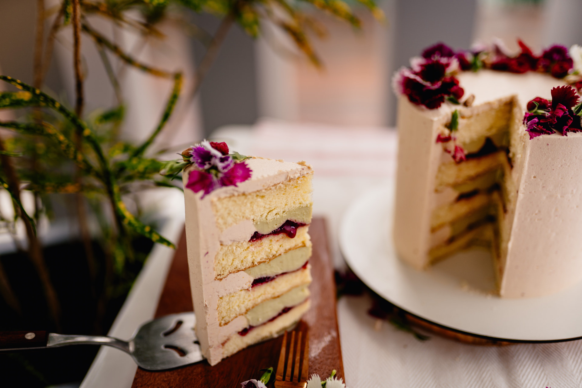 Porción de pastel en capas con relleno de frutos rojos y flores comestibles